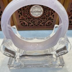Polished lavender jade circle resting on lucite holder