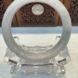 Translucent pale grey jade bangle on clear stand