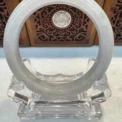 White jade ring on crystal stand.