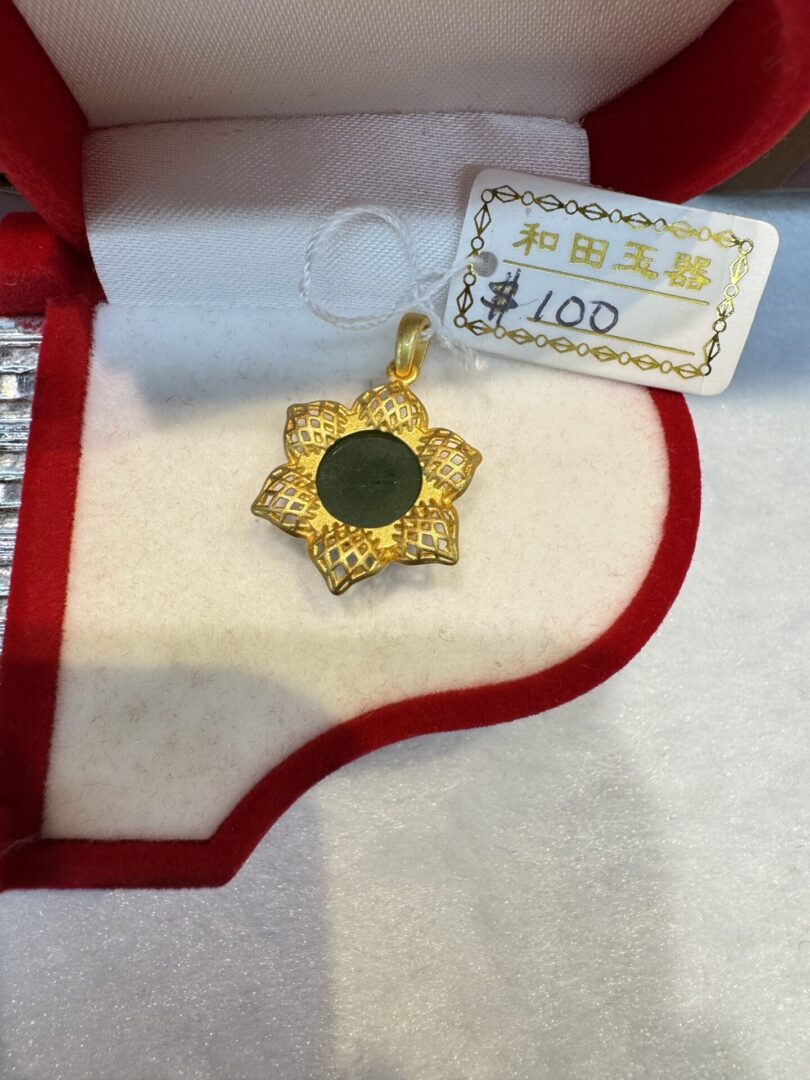 Gold flower pendant in red jewelry box.