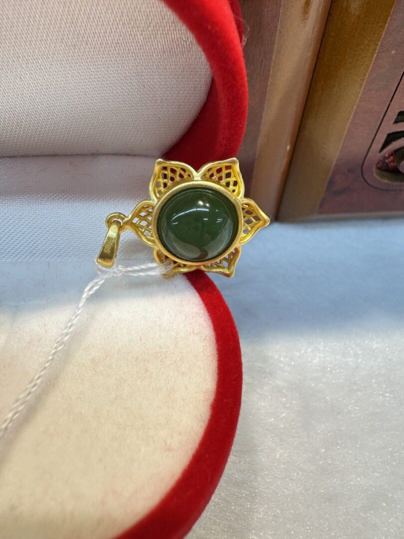 Gold floral brooch with green stone.
