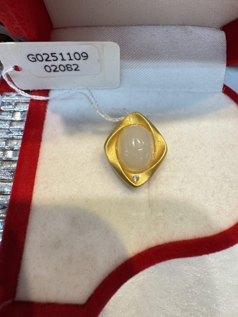 Gold pendant with milky oval and diamond