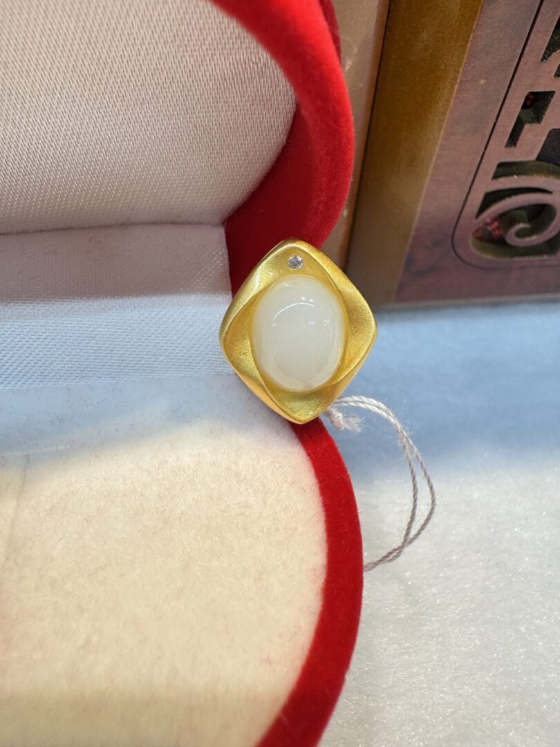 Gold ring with white stone in box.