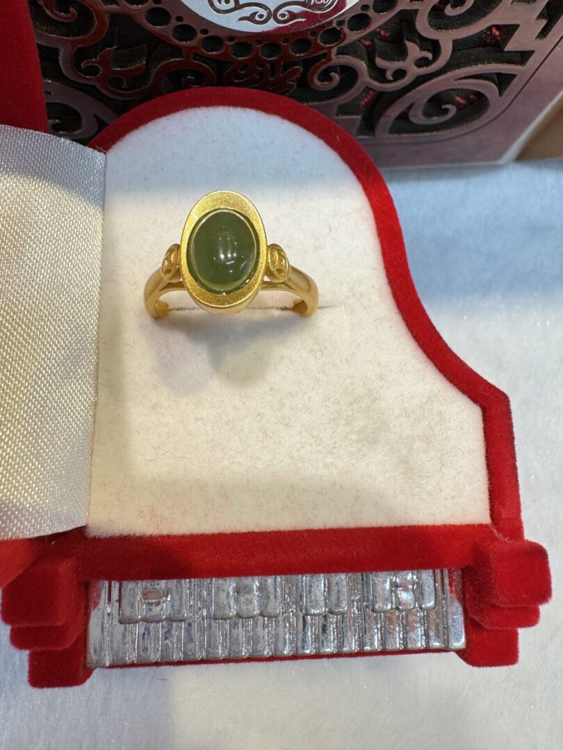 Oval green stone set in textured gold bezel