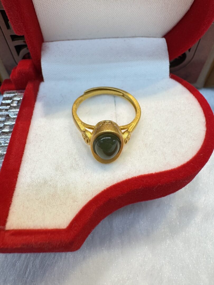 Gold ring with gemstone in red box.