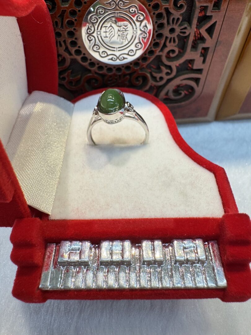Green gemstone ring in red decorative box.