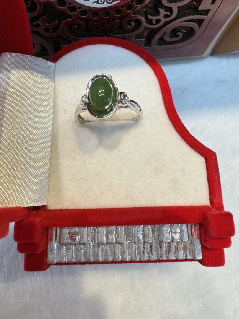 Silver ring with green stone in box.