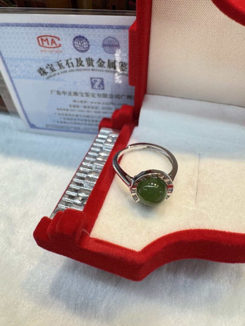 Green gemstone ring in red velvet box.
