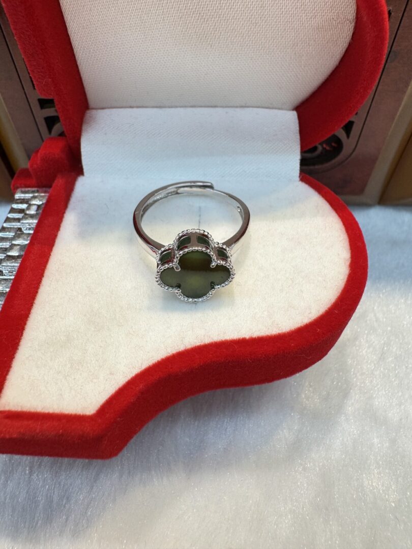 Silver ring with green clover in box.
