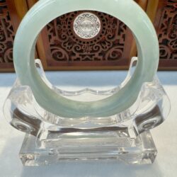 Seafoam jade bangle showcased against carving