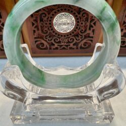 Vivid green mottled jade bangle displayed