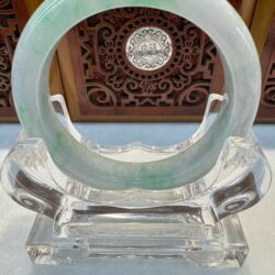 Circular jade bangle before ornate wooden panel