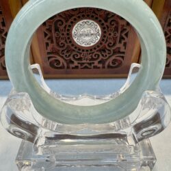 Jade bangle showcased before carved panel