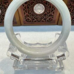 Glossy pale jade bangle displayed on acrylic base