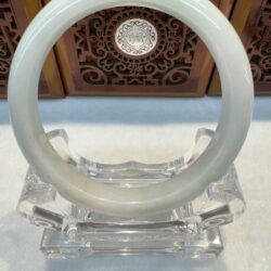 Smooth white jade bangle on acrylic stand