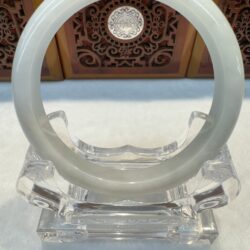 Round white jade bracelet on acrylic stand