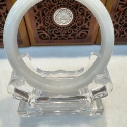 Handcrafted white jade bangle on pedestal