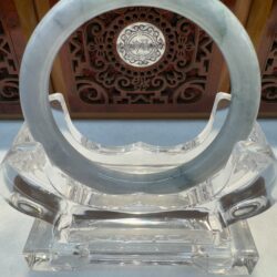 Round grey-green jade bangle framed by carving