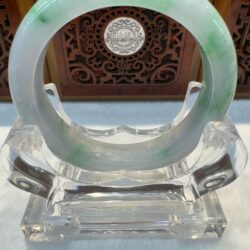 Green-white jade bangle on crystal stand