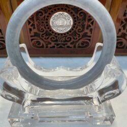 Crystal circular sculpture on decorative stand.