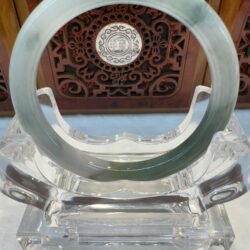 Translucent green jade bangle on acrylic stand